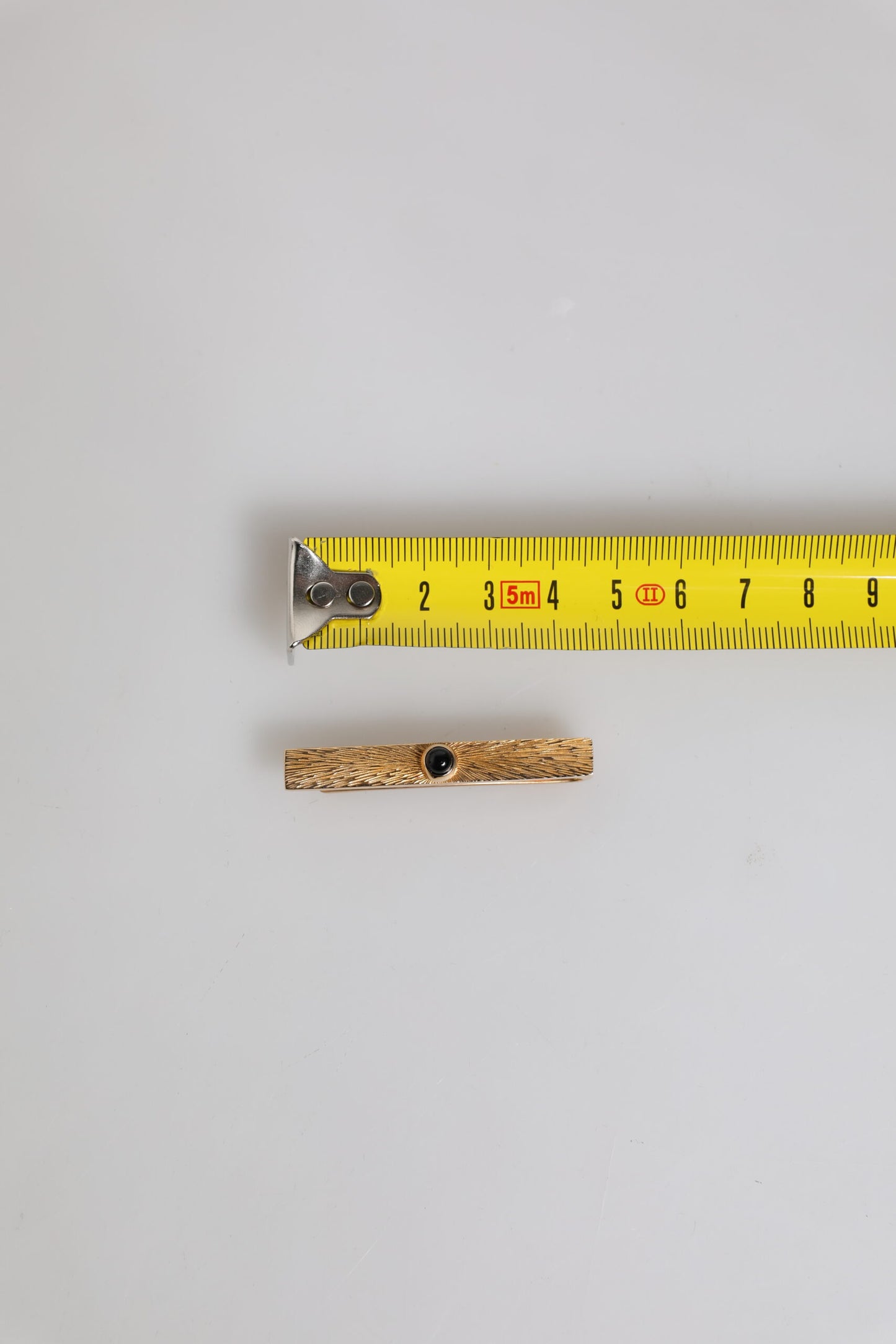 Dolce & Gabbana – Krawattenklammer aus Messing in Goldtönen mit schwarzem Saphir